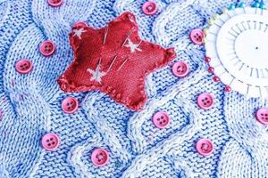 belle texture d'un pull naturel doux et chaud, de tissus tricotés et de petits boutons ronds rouges pour la couture et d'un tampon à aiguille. mise à plat. l'arrière-plan photo