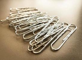 trombones en métal blanc pour maintenir les documents ensemble de manière normale. papeterie pour travailler avec des documents au bureau photo