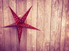 grandes étoiles de vacances rouges mignonnes, noël, décoration du nouvel an sur fond de gerlyand rougeoyant sur des planches verticales en bois avec coutures photo