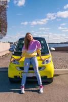 belle femme debout près d'une voiture jaune par une journée ensoleillée photo