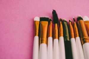 un ensemble de belles brosses douces différentes pour le maquillage de la sieste naturelle pour le ciblage de la beauté et l'application d'un fond de teint tonal dans un support et un espace de copie sur un fond rose, violet photo