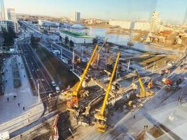 construction d'un nouveau viaduc au centre-ville. de grandes grues de construction jaunes construisent un pont à partir de poutres lourdes photo