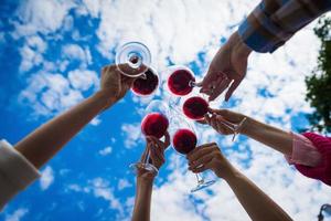 les gens trinquent avec du vin sur la terrasse d'été du café ou du restaurant photo