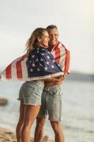 couple avec drapeau national américain passant la journée sur une plage photo