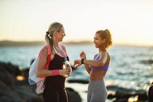 maman et fille adulte pendant la pause de l'entraînement en plein air près de la mer photo