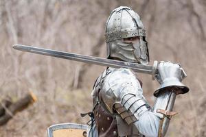 noble guerrier. portrait d'un guerrier médiéval ou d'un chevalier en armure et casque avec bouclier et épée posant photo