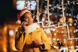 femme noire utilisant un smartphone dans la ville au moment de noël photo