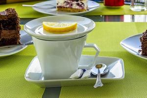 tasse de thé en porcelaine blanche avec citron, sucre, cuillère sur une table à la cafétéria.