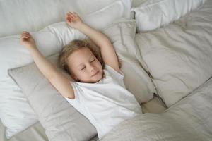 petite fille enfant dormant dans son lit, allongée sur un oreiller en coton doux dans la chambre. sommeil sain des enfants photo
