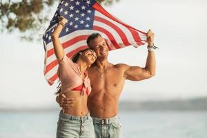 couple avec nous drapeau national passer la journée sur une plage photo