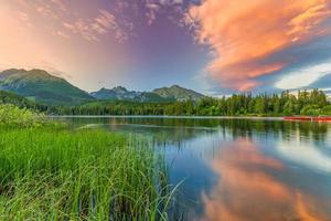 paysage de coucher de soleil d'automne avec lac de montagne paisible et tranquille. calme nature en automne. lever du soleil sur le lac brumeux avec feuillage d'automne et montagnes, ciel de nuages incroyable. feuillage de la nature fantastique photo