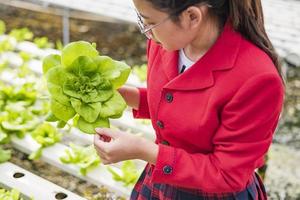 une belle biotechnologiste asiatique recueille des feuilles de laitue pour la recherche avec du brocoli dans une ferme biologique. produits de bonne qualité. n'oubliez pas de planter des plantes. notion de jour de la terre. photo