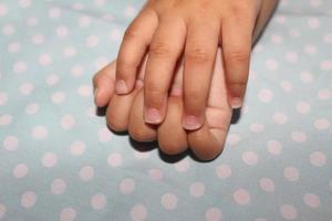 Les ongles de bébé de 11 mois sont longs, une petite partie des ongles est cassée et il y a de la saleté car ils n'ont pas été coupés. photo