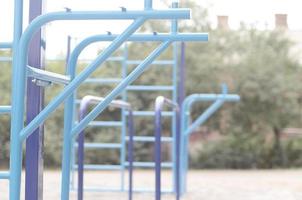 bars sportifs en bleu sur le fond d'un terrain de sport de rue pour l'entraînement en athlétisme. équipement de gym athlétique en plein air. photo macro avec mise au point sélective et arrière-plan extrêmement flou