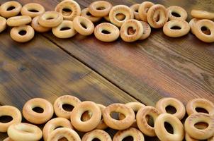 beaucoup de bagels jaunes frais se trouvent à la surface du vieux bois sombre. un type populaire de produits à base de farine. l'une des friandises russes traditionnelles pour le thé photo