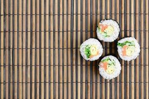 les rouleaux de sushi reposent sur un tapis de couture en paille de bambou. cuisine asiatique traditionnelle. vue de dessus. minimalisme à plat tourné avec espace de copie photo