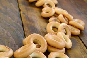 beaucoup de bagels jaunes frais se trouvent à la surface du vieux bois sombre. un type populaire de produits à base de farine. l'une des friandises russes traditionnelles pour le thé photo