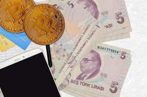 Billets de 5 lires turques et bitcoins dorés avec smartphone et cartes de crédit. concept d'investissement en crypto-monnaie. minage ou commerce de crypto photo