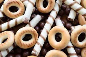 beaucoup de tubules sucrés croustillants, de boules fondantes au chocolat et de bagels jaunes reposent sur une surface en bois. vue rapprochée photo