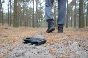 jeune homme perd son sac à main avec des billets en euros sur le chemin du bois de sapin d'automne russe. insouciance et perte de concept de portefeuille photo