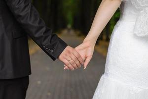 un homme tient la main d'une femme. mains de la mariée et du marié avec un gros plan de bague de mariage photo