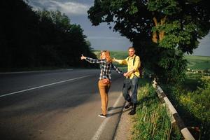 un jeune couple d'amoureux élégant et heureux attrape une voiture dans les montagnes. notion d'auto-stop photo