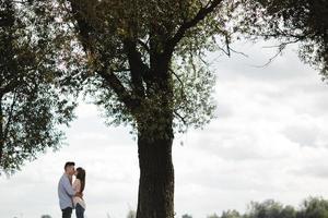 jeune couple romantique s'amuse en été journée ensoleillée près du lac. profiter de passer du temps ensemble en vacances. l'homme et la femme s'embrassent et s'embrassent. photo