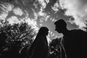 photographie en noir et blanc. silhouette d'un jeune couple aimant s'amuse à l'extérieur. amour et tendresse, rencontres, romance, concept de famille photo
