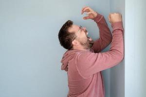 l'homme est bouleversé et désespéré, il crie ou pleure fort, debout contre le mur. espace de copie. photo