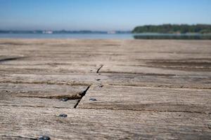 ancienne jetée faite de planches en bois patinées avec des clous, sur fond de lac et de ciel bleu, par une journée ensoleillée d'été. photo