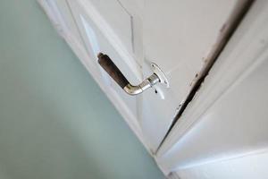 ancienne poignée de porte sur une porte en bois blanche, à l'intérieur. fermer. vue de dessus. photo