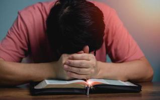 les gens se tenant la main la tête inclinée vers le bas prient Dieu dans le livre du milieu livre de la sainte bible avec collier croisé devant la sainte bible. photo