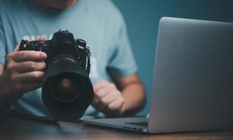 jeune homme apprenant à utiliser et à régler l'appareil photo reflex numérique à partir d'un cours vidéo en ligne.