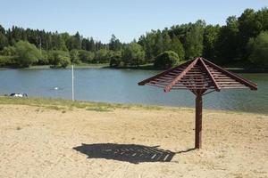 plage sur le lac. sable sur le rivage. endroit pour se détendre. plage sans personne. parapluie du soleil sur le rivage. photo