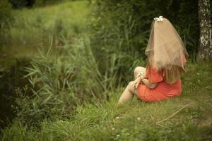 fille au bord du lac en été. jeune fille en vêtements orange. mariée en robe. vacances dans le parc. photo