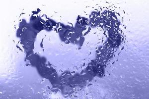 coeur violet sous la surface du verre avec des gouttes d'eau à proximité. fond de valentines, amour, concept de date photo