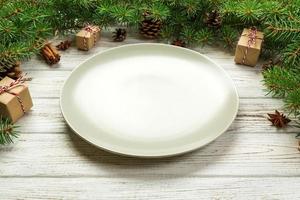 vue de perspective. assiette vide en céramique ronde sur fond de noël en bois. concept de plat de dîner de vacances avec un décor de nouvel an photo