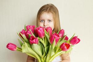 portrait de petite fille avec bouquet de fleurs tulipes dans ses mains photo