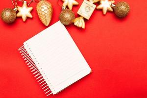 Boules et jouets de Noël dorés avec feuille de note vierge vide sur fond rouge photo