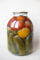 boîte gâtée de coutures de légumes. bocal en verre avec tomates et concombres marinés maison avec champignon blanc photo