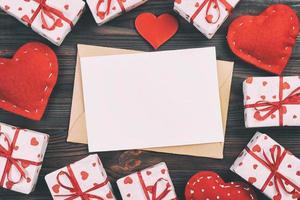 saint valentin ou autre cadeau de vacances fait à la main en papier avec des coeurs rouges et une boîte de cadeaux dans un emballage de vacances. boîte cadeau présente sur la vue de dessus de table en bois foncé avec espace de copie, espace vide pour la conception photo