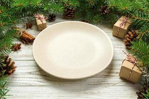 vue de perspective. assiette vide en céramique ronde sur fond de noël en bois. concept de plat de dîner de vacances avec un décor de nouvel an photo