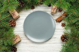 vue de dessus. assiette vide en céramique ronde sur fond de noël en bois. concept de plat de dîner de vacances avec un décor de nouvel an photo