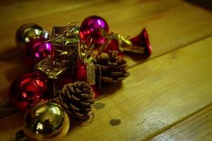 décorations sur le thème du nouvel an et des cadeaux de noël sur fond en bois, composées d'une boîte cadeau dorée. boules colorées brillantes pommes de pin séchées et petites cloches espace libre pour la conception photo