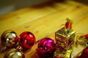 décorations sur le thème du nouvel an et des cadeaux de noël sur fond en bois, composées d'une boîte cadeau dorée. boules colorées brillantes pommes de pin séchées et petites cloches espace libre pour la conception photo