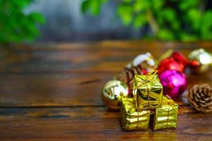 décorations sur le thème du nouvel an et des cadeaux de noël sur fond en bois, composées d'une boîte cadeau dorée. boules colorées brillantes pommes de pin séchées et petites cloches espace libre pour la conception photo