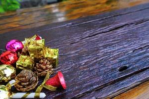 décorations sur le thème du nouvel an et des cadeaux de noël sur fond en bois, composées d'une boîte cadeau dorée. boules colorées brillantes pommes de pin séchées et petites cloches espace libre pour la conception photo