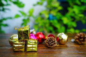 décorations sur le thème du nouvel an et des cadeaux de noël sur fond en bois, composées d'une boîte cadeau dorée. boules colorées brillantes pommes de pin séchées et petites cloches espace libre pour la conception photo