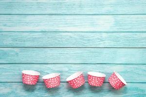 étuis à cupcakes roses à pois sur un plancher en bois bleu. matériel de cuisson. photo