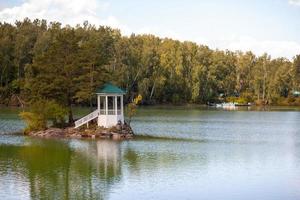 une petite île magnifique sur le lac aya dans le territoire de l'altaï ou la république de l'altaï. il y a un petit belvédère sur l'île et une forêt autour du lac. photo